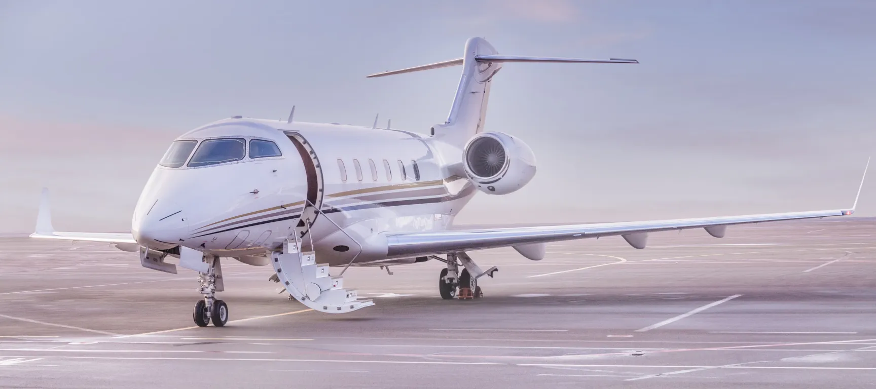 Private jet parked on an airport ramp with the cabin door open at dawn, representing private aircraft acquisition, aircraft brokerage, and ownership readiness before its first mission.