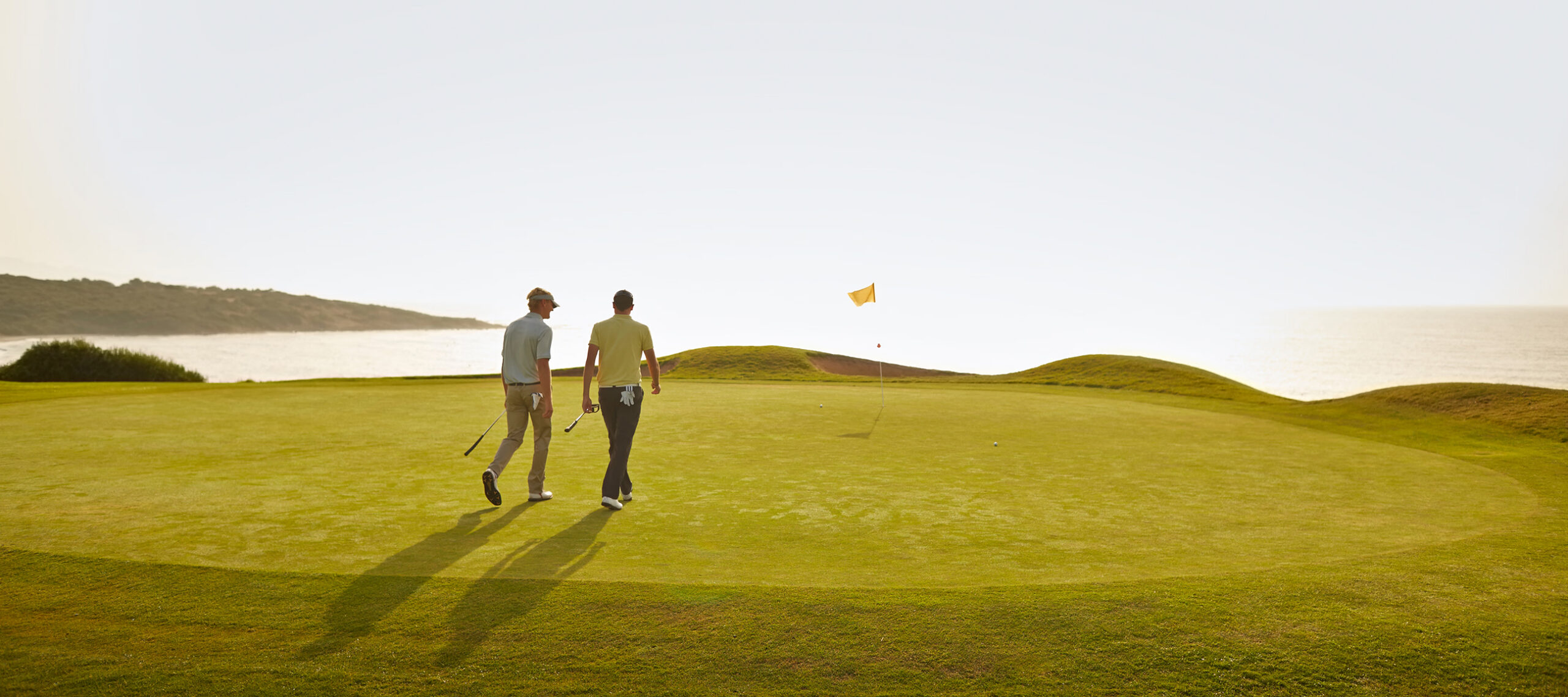 Two business professionals walking a coastal golf course, representing the relationships and opportunities that private jet travel helps protect when time and distance matter.