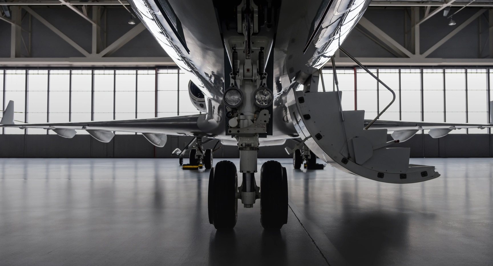 Private jet parked inside a hangar with the cabin door open, representing the personalized aircraft and ownership solutions available through FLYUSA’s fractional ownership program.