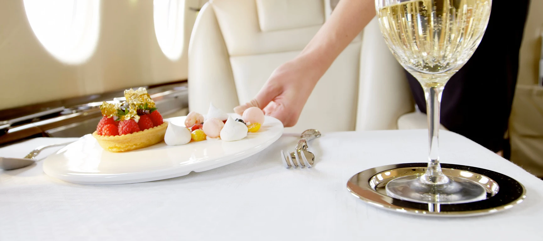 Cabin attendant serving inflight dining and champagne inside a private jet cabin, highlighting the comfort and personalized service of the FLYUSA Jet Card.