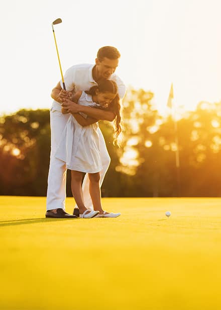 Parent teaching a child to play golf at sunset, representing how private jet charter gives business leaders more time for family, relationships, and the moments that matter most.